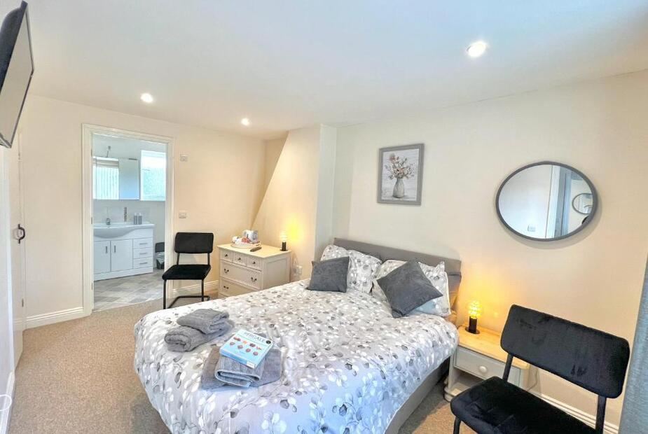 Double bedroom with floral bedding, round mirror and bedside lamps