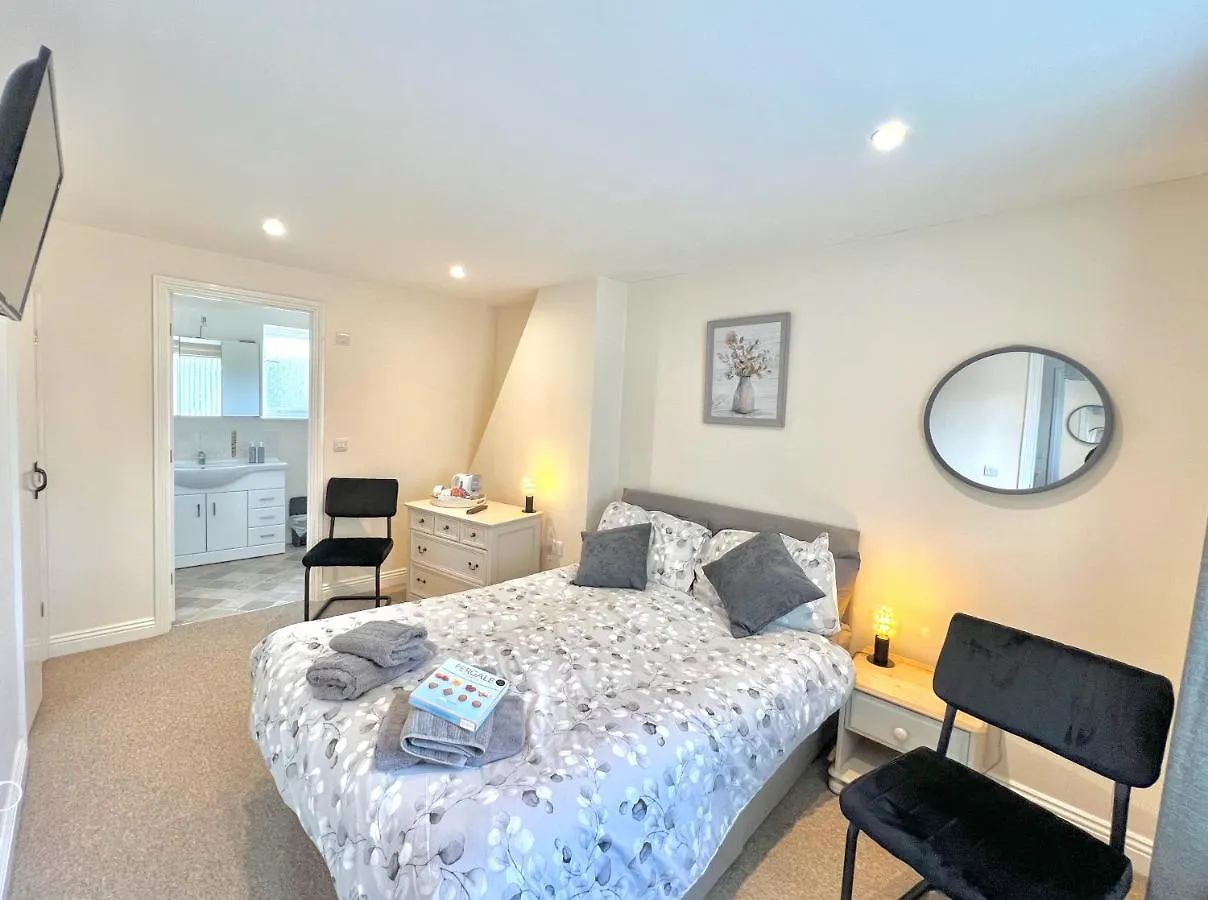 Second double bedroom with TV, bedside lamps and en-suite bathroom beyond the open door
