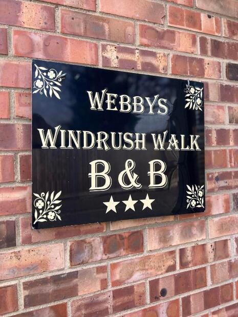 Webby's Windrush Walk B&B name plaque on the brick wall outside